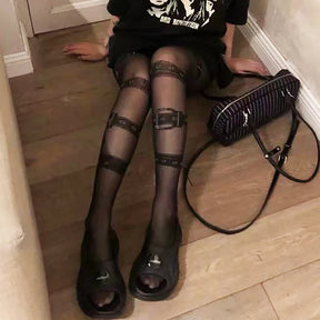 Full-length view of black gothic belt print pantyhose styled with a skirt and dark shoes.