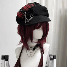 Red plaid gothic newsboy cap on a mannequin, showing its curved brim, decorative chains and dangling cross charm.