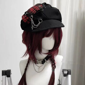 Red plaid gothic newsboy cap on a mannequin, showing its curved brim, decorative chains and dangling cross charm.
