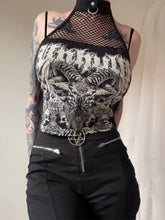 Front view of the black graphic crop top, showing white Baphomet-inspired artwork below a fishnet panel and ring-detail neck band.