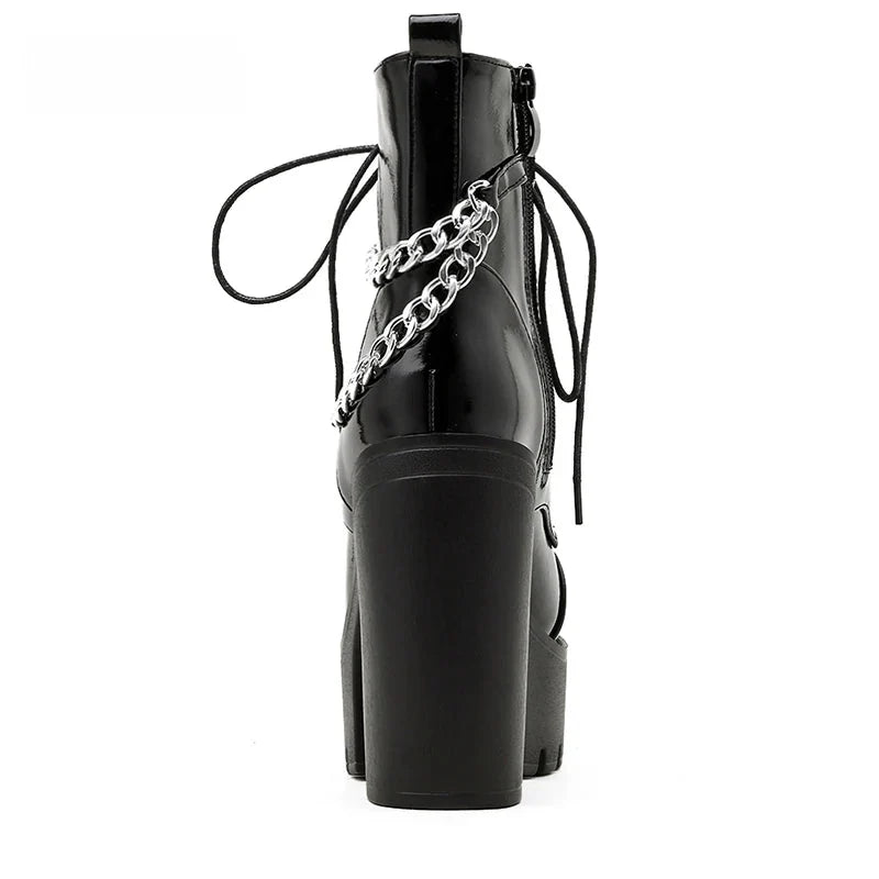 Rear view of a glossy black platform boot on white, showing the tall block heel, pull tab and silver-tone chains around the ankle.