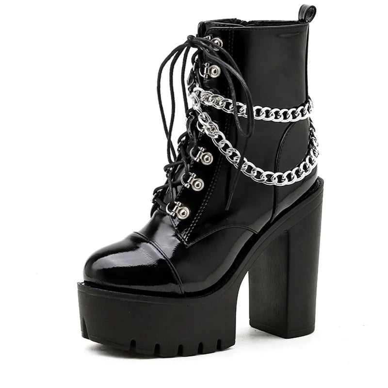 Single glossy black platform ankle boot angled on white, showing its front laces, draped silver-tone chains and tall block heel.