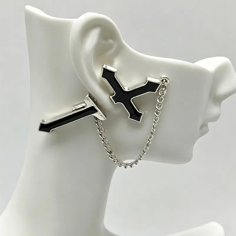 Black split cross chain earring placed on a white ear display, showing how the upper and lower sections sit around the earlobe.