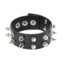 Black cuff bracelet against white with two rows of silver-tone spikes and multiple snap positions visible inside the band.