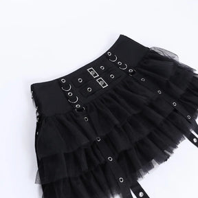 Black ruffle skirt laid diagonally on white, displaying the rectangular front hardware, rows of rings and gathered layers.