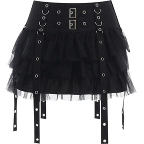 Black eyelet strap mini skirt isolated on white, showing two rectangular front buckles, rows of rings and layered mesh ruffles.