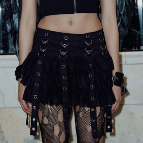 Square front outfit view of the black ring and eyelet strap skirt with a black crop top and torn-pattern tights.