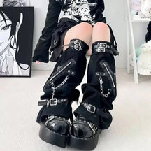 Close front view of black gothic leg warmers with buckle straps, diagonal zippers, chains and flared openings over platform shoes.