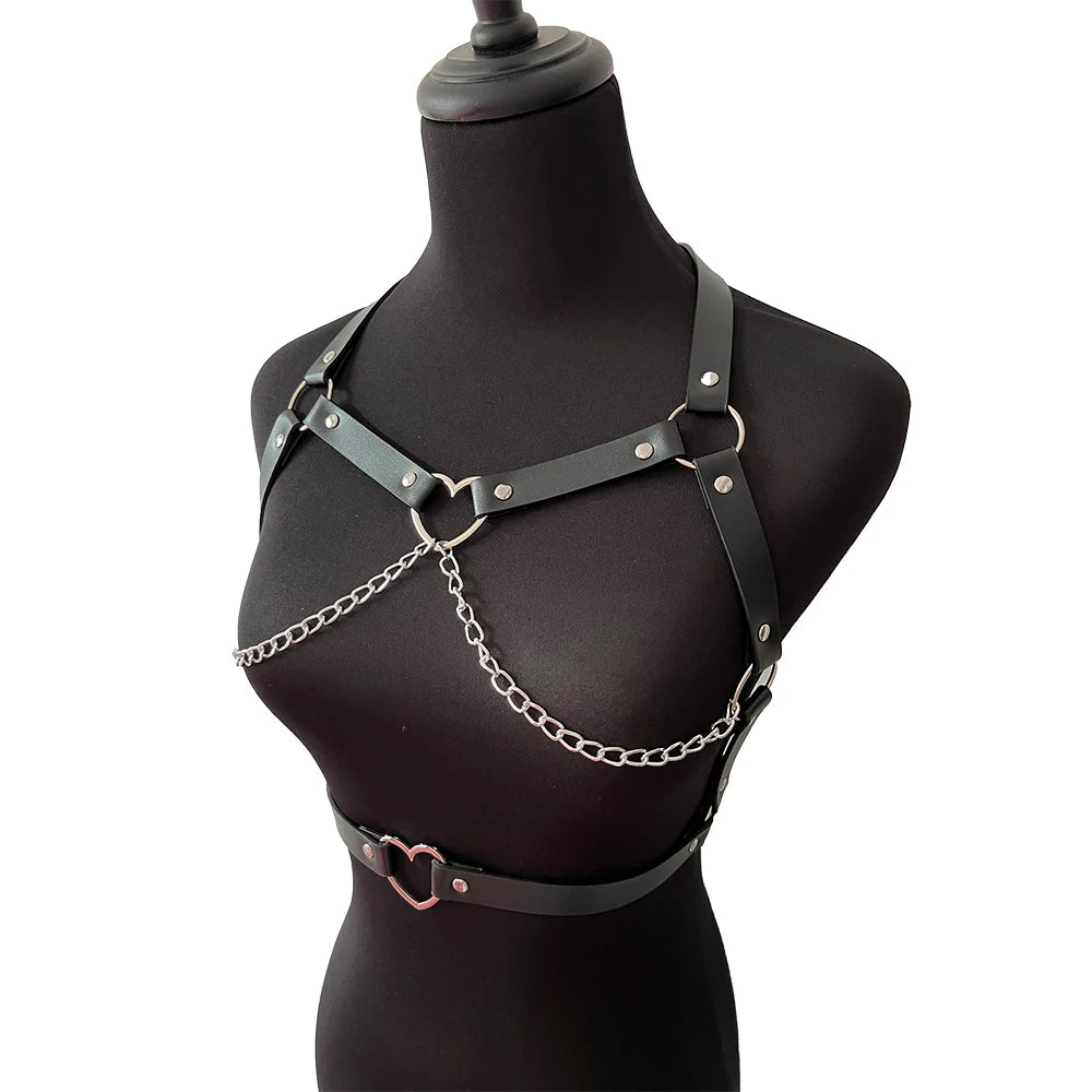Angled view of the black harness set, showing the heart-shaped chest ring, curved chains and separate heart ring belt against a black mannequin.