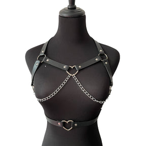 Black heart ring harness and matching waist belt on a black dress form. Two silver-tone chains drape across the chest beneath narrow riveted straps.