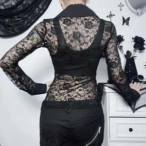 Rear view of the black blouse shows floral lace across the upper back and sleeves, with the separate black underlayer visible beneath.
