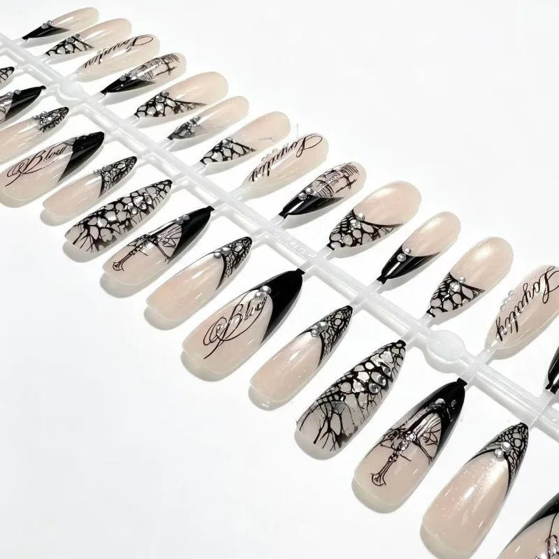 Close view of black lace and nude French press-on nail tips on a white display sprue, showing the fine printed patterns.