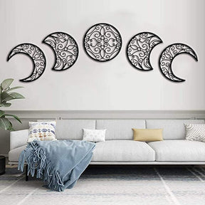 Black moon-phase wall art in a broad arc above a pale sofa, with a plant and blue throw in the room.