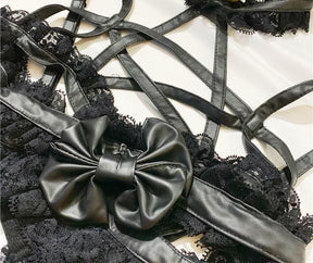 Close-up of the large black bow and glossy pentagram straps over the lace-trimmed lingerie top.