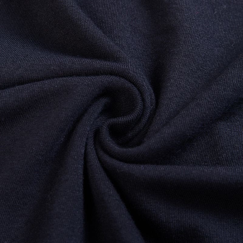 Close-up of the black bodycon dress fabric gathered into a swirl, showing its fine knit surface.