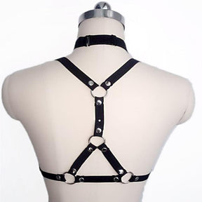 Back of a black chest harness on a mannequin, with a choker band, central vertical strap, upper O-ring and triangular lower strap arrangement.