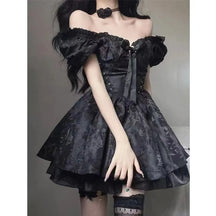 Black gothic mini dress worn with gathered puff sleeves and a large bow at the neckline. The fitted lace-up bodice opens into a floral jacquard skirt with a ruffled layer beneath.