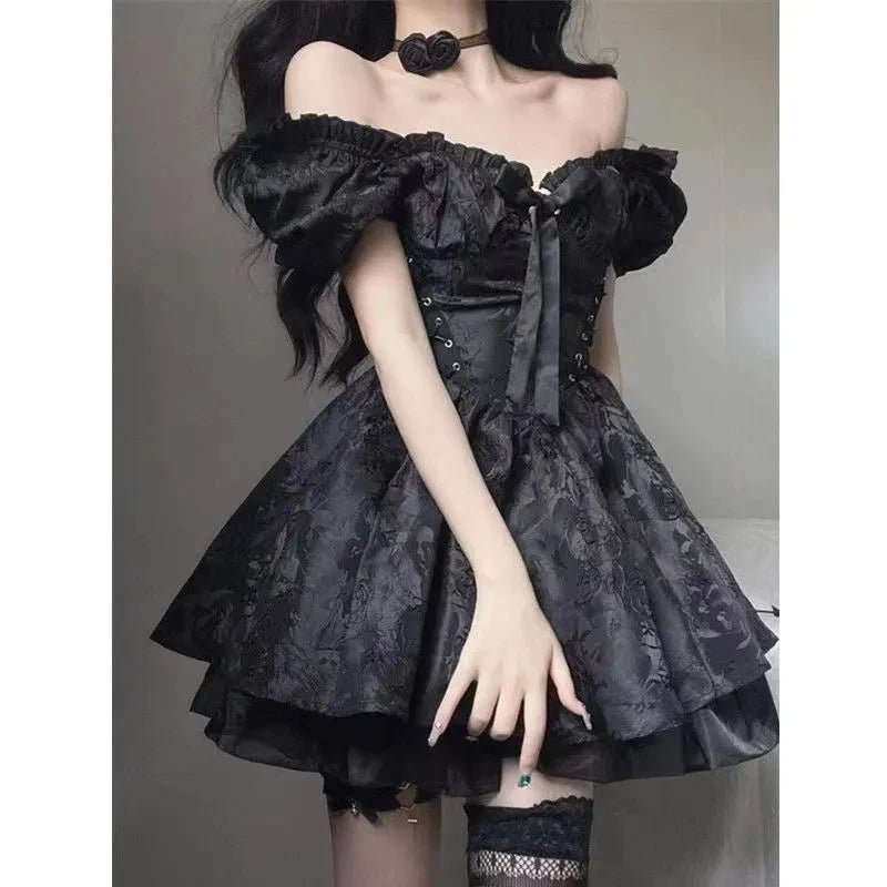 Black gothic mini dress worn with gathered puff sleeves and a large bow at the neckline. The fitted lace-up bodice opens into a floral jacquard skirt with a ruffled layer beneath.