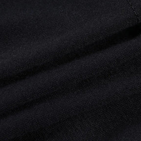 Close view of the black ruffle skirt fabric folded to show its smooth dark surface and fine texture.