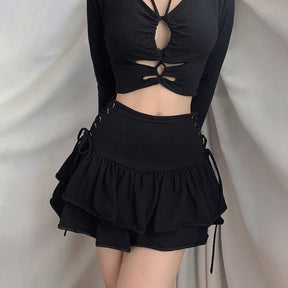Square front outfit view showing the black skirt's broad waistband and two gathered ruffle tiers below a black cutout top.