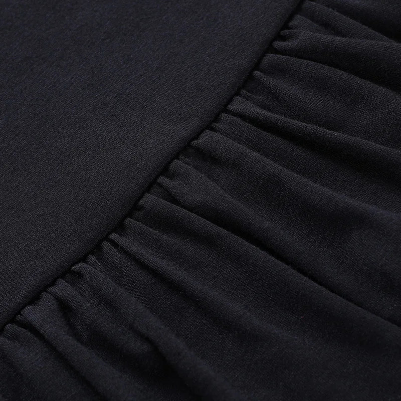 Close-up of the seam where the black skirt's smooth waistband meets its gathered upper ruffle.