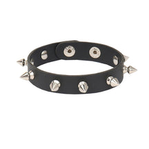 Narrow black cuff bracelet against white with a single row of silver-tone spikes and adjustable snap fastenings.