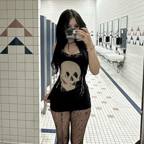 Square mirror photograph of the black skull mini dress with patterned tights, showing the pale skull and lace hem against a tiled background.