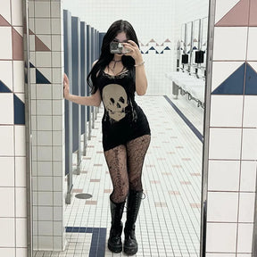 Full-length mirror outfit view of the black skull dress, patterned tights and black footwear in a tiled room.