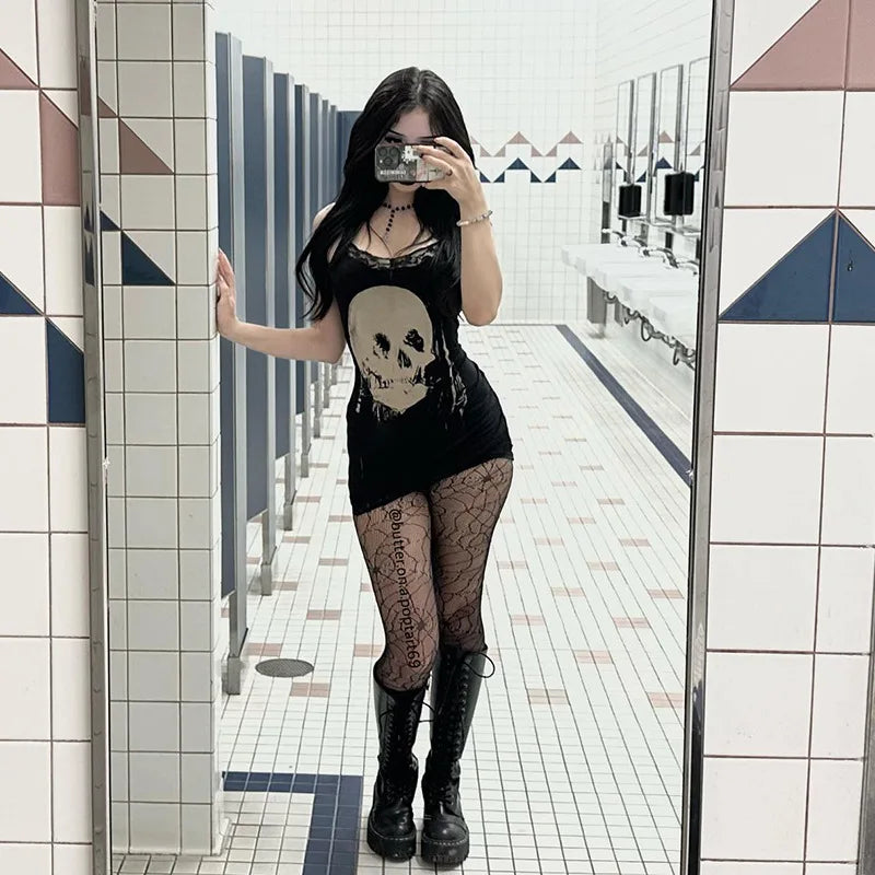 Full-length mirror outfit view of the black skull dress, patterned tights and black footwear in a tiled room.