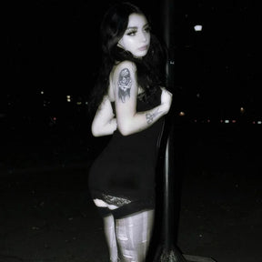 Rear nighttime model view of the black mini dress, showing the plain back and lace trim at the short hem.