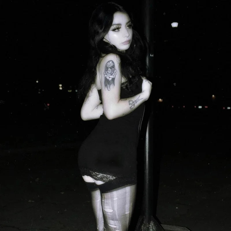Rear nighttime model view of the black mini dress, showing the plain back and lace trim at the short hem.
