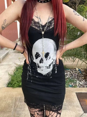 Front outdoor model view of the black skull dress with hands at the waist, showing the lace neckline, large skull artwork and short lace-trimmed hem.