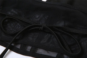 Detail of the black top's back ties resting over its sheer mesh band.