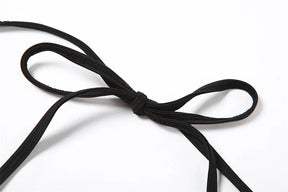 Close view of the black halter neck ties knotted into a bow against white.