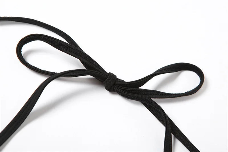 Close view of the black halter neck ties knotted into a bow against white.