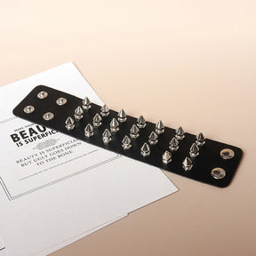 Wide black spiked and studded bracelet opened flat, showing the arrangement of hardware and multiple snap positions at its ends.