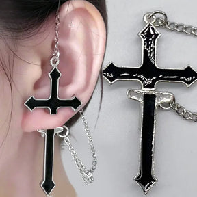 Two-panel close-up of a black split cross earring worn on an ear beside a flat detail of its glossy black centre and silver-tone outline.
