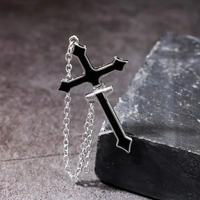 Single black split cross chain earring arranged on a dark textured surface, showing its angular outline, silver-tone edges and hanging chain.