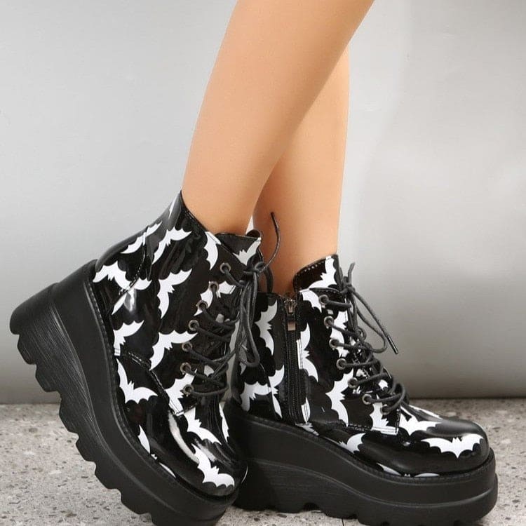 Angled upper view of black platform boots with white bats, showing the laced fronts, rounded toes and silver-tone eyelets.