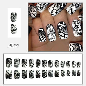 Black-and-white square nail design with decorated skulls, spiderwebs and crossed bone motifs, shown worn and arranged by size.
