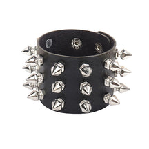 Wide black cuff against white, showing its mixed arrangement of pointed spikes, geometric studs and interior snap closures.
