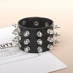Wide black cuff bracelet standing upright, with rows of faceted silver-tone studs between pointed spikes at the edges.