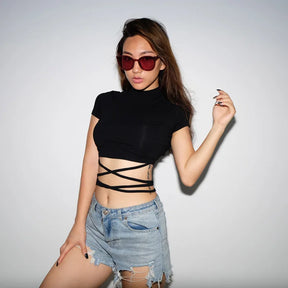 Front studio outfit view of the black short sleeve wrap top with denim shorts and red sunglasses.