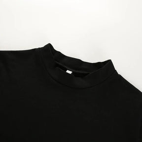 Angled close view of the black crop top's round neckline and narrow stitched neck edge.