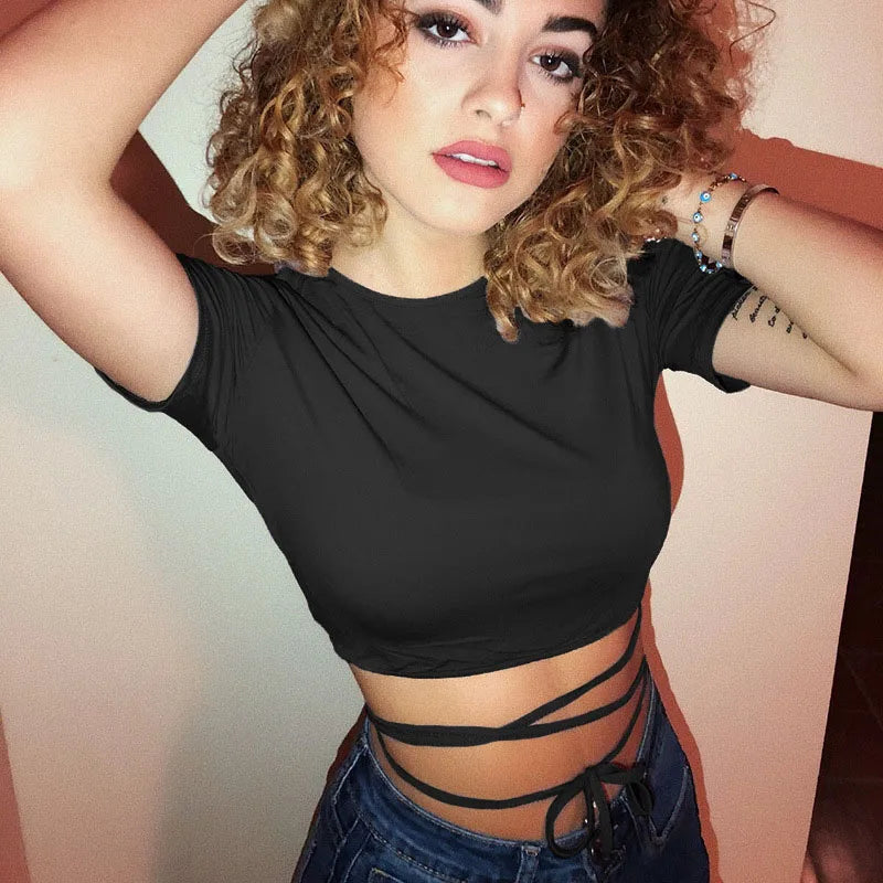 Closer model photograph of the black round-neck crop top, with one arm raised and the waist ties visible above jeans.