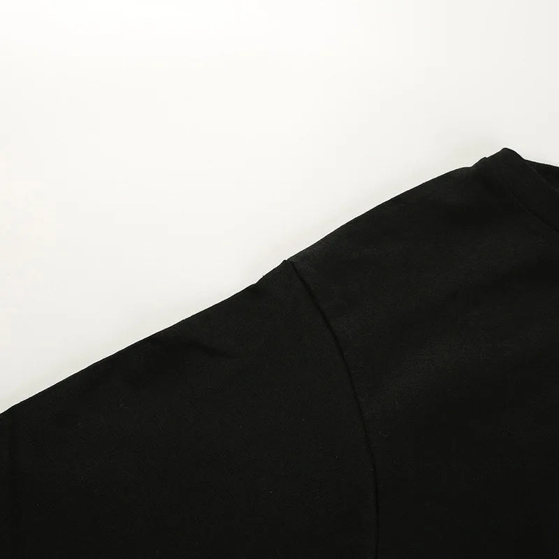 Close-up of the black top's shoulder and sleeve seam against a white surface.