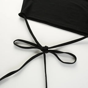 Long black waist ties arranged in a bow below the cropped hem on a white surface.