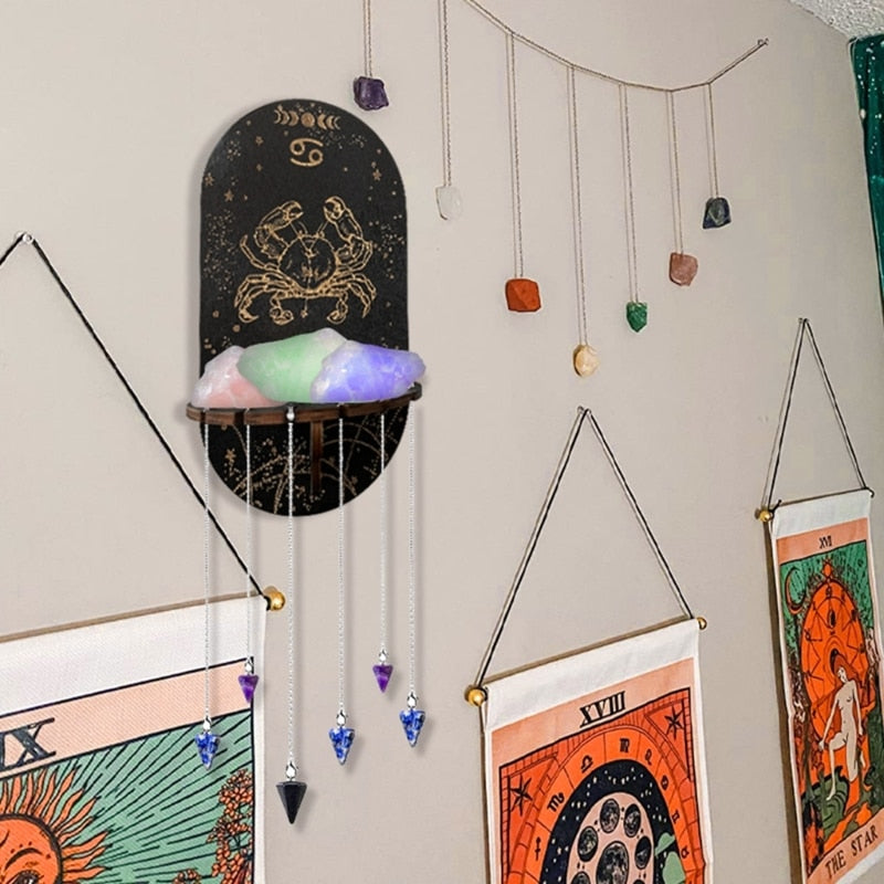 Cancer zodiac wall shelf styled with coloured stones on the ledge and pendants hanging below, beside a decorative wall garland.