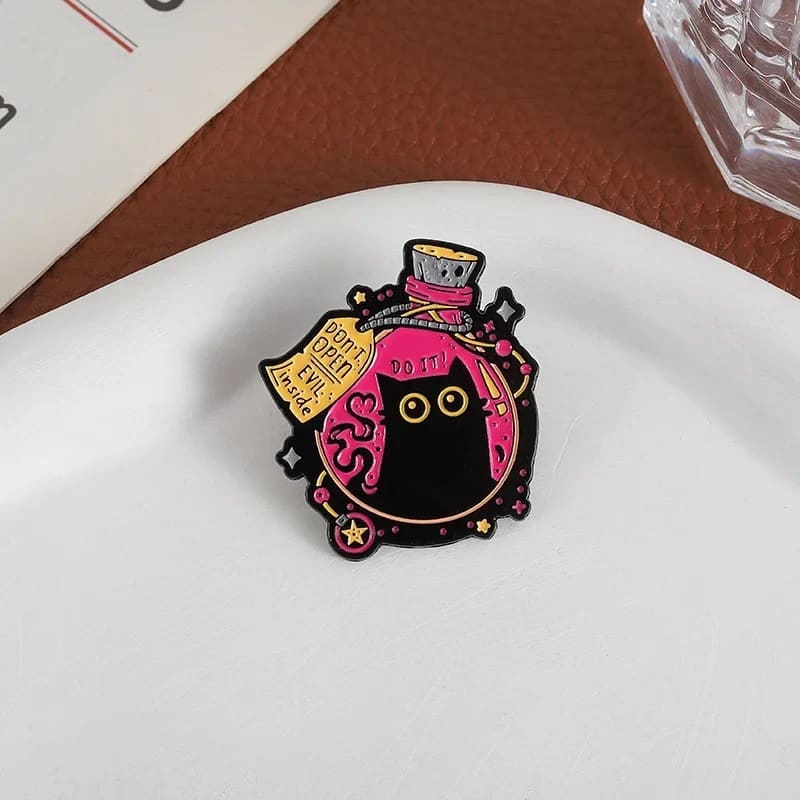 Black cat potion bottle enamel pin on a white dish, showing the warning tag and tiny “DO IT!” lettering.
