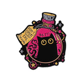 Black cat potion bottle enamel pin with pink enamel, gold-tone stars and a “Don’t Open! Evil Inside” tag on white.